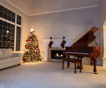 在客厅的圣诞树亮夜里烧壁炉和大钢琴图片
