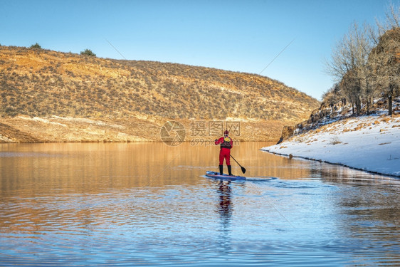 穿红色干衣的男球正在科罗拉多山湖冬季风景中划踏板图片