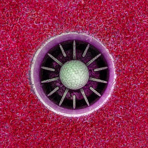 一洞高尔夫球在杯子里粉红色图片