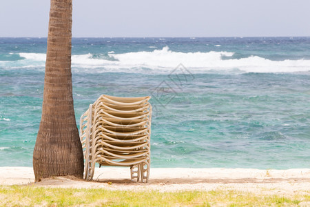 在热带白色沙滩上在棕榈树下堆叠沙椅图片