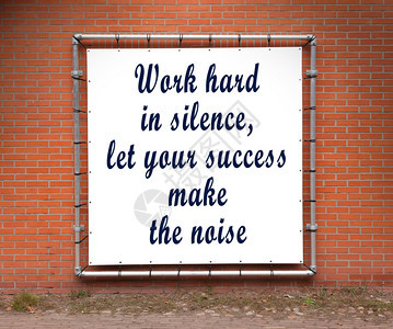 大横幅在砖墙上加鼓舞人心的引号在沉默中努力工作图片