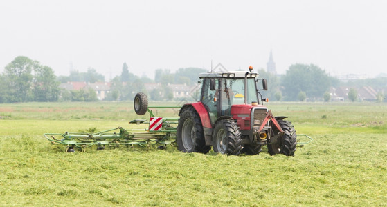 农民用拖拉机在干燥的田地上撒草图片