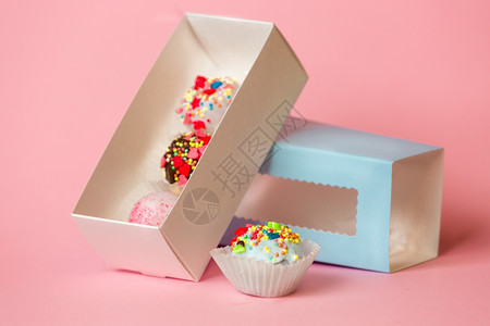 张开的礼物盒上面有彩色蛋糕球和糖果上面喷洒粉红背景的糖果图片