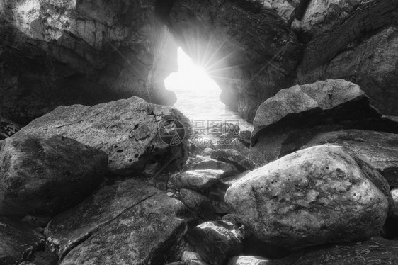葡萄牙Ursa海滩岩石拱门的阳光照单色片图片