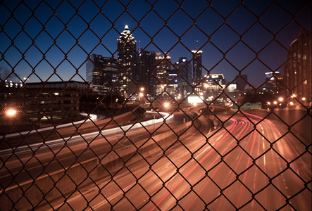 透过铁丝网栅栏的夜间城市天际抽象模糊的城市景色背图片