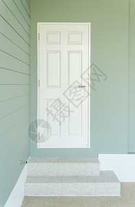 蓝色墙上的白门和通往入口的两步图片