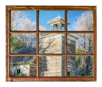 在内布拉斯加州农村的旧废弃校舍从古老的被用脏玻璃砸的被打碎窗户中看到图片