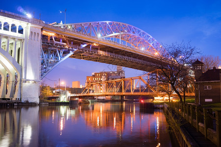 夜幕降临在河上一座桥载着交通进入城市图片