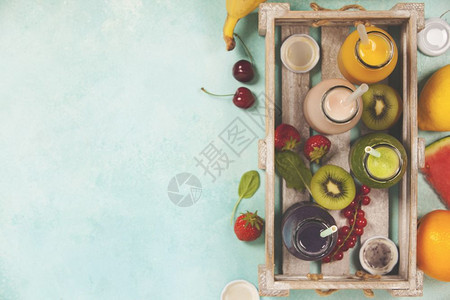 新鲜果汁或以蓝底顶视有选择的焦点木盘中水果和蔬菜制成的鲜果汁和脱毒饮食清洁素健康生活方式概念图片
