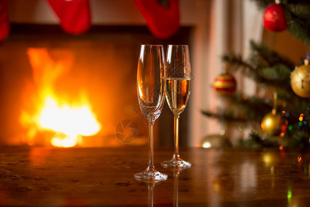 在燃烧的壁炉前玻璃杯和香槟放在桌上图片