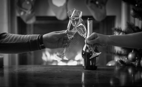 男女一起庆祝圣诞节在壁炉上把杯子和香槟连在一起图片
