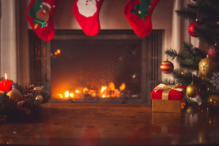 紧贴红色圣诞礼物盒配有金丝带旁边装饰圣诞树和壁炉图片