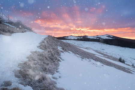 日出时山雪的冬季峰全景图片