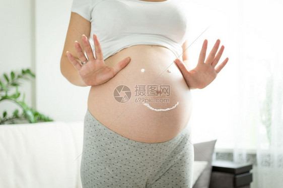满笑容的孕妇被克瑞姆为腹部伸展痕所吸引的笑容图片