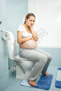 坐在厕所的年轻患病孕妇图片