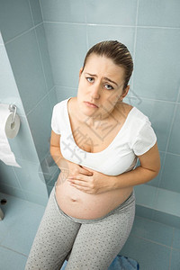 愤怒的孕妇使用厕所感到不舒服的肖像图片