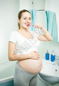 清晨在浴室刷牙的美丽孕妇肖像图片