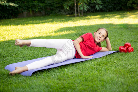 年轻微笑的女孩在公园草地上运动图片