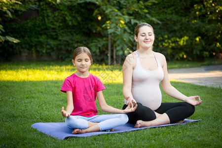 怀孕母亲和女儿在公园冥想图片