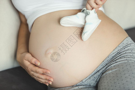 紧闭肚子上婴儿袜的孕妇图片