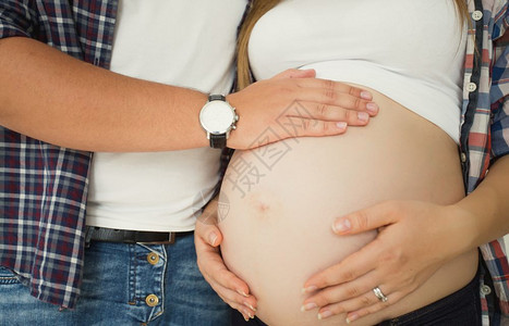 年轻人触摸怀孕妻子和腹部的近距离照片图片