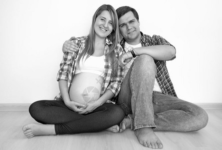 坐在地板上看着对方的幸福怀孕夫妇黑白画像图片
