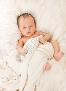 新生婴儿男孩躺在毯子下床上图片