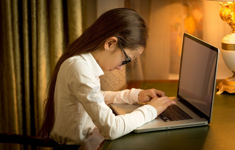 坐在桌后内阁用笔记本电脑的女学生图片