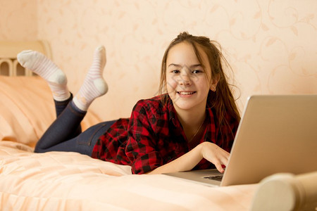 坐在床上并使用笔记本电脑的笑少女快乐图片