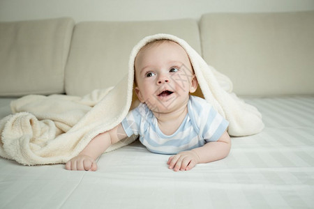 快乐的小婴儿爬在床上毯子的下图片