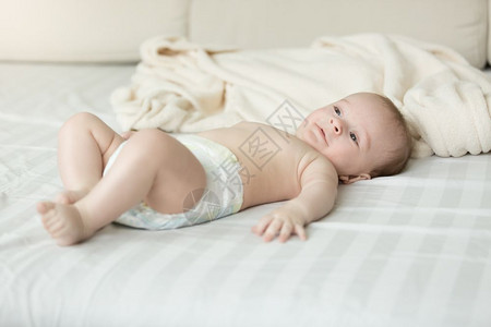 穿着尿布躺在床上的可爱男孩图片