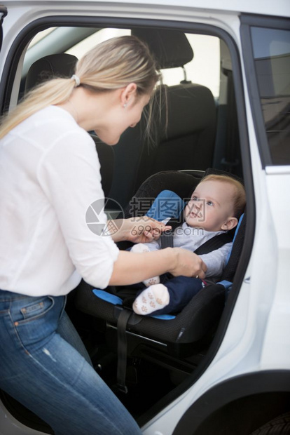 把她的婴儿放在汽车安全座椅上图片