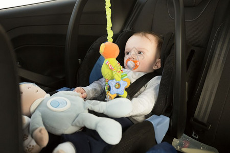 坐在汽车座椅上玩玩具的婴儿图片