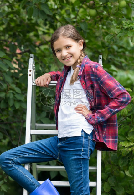 微笑的女孩站在果园的继板顶上图片