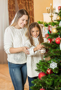 少女帮助母亲装饰圣诞树图片