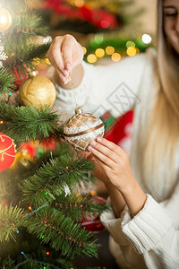 在圣诞树上放金黄酒的年轻女子近身背景图片