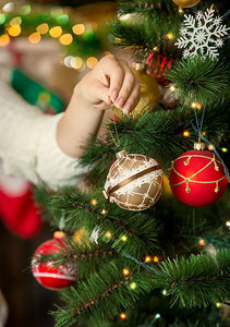 年轻女子在圣诞树上放金黄泥的画面图片