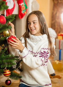 在客厅装饰圣诞树的漂亮女孩图片