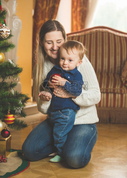 微笑的母亲和婴儿男孩装饰圣诞树配上图片