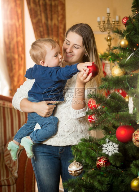 快乐的年轻女人与她的儿子装饰圣诞树图片