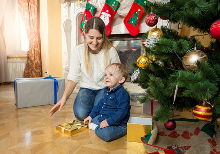 母亲与她的儿女一起坐在壁炉和圣诞树旁边客厅的地板上背景图片
