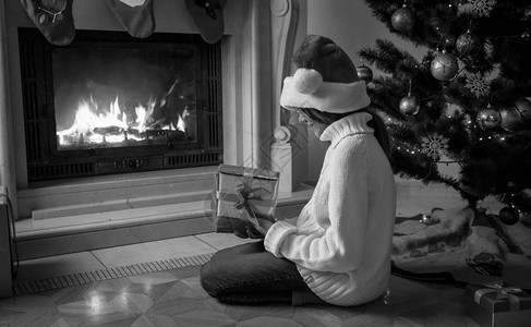 女孩拿着礼物盒坐在旁边壁炉的黑白画面图片