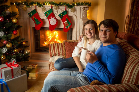 快乐的年轻家庭在壁炉沙发上喝茶图片