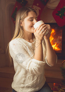 美丽的年轻女子在壁炉喝茶的肖像图片