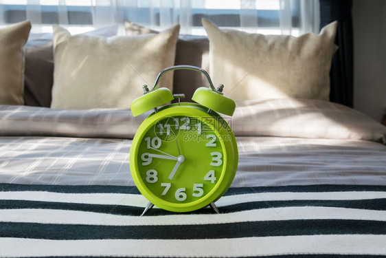 现代卧室床上的绿色闹钟图片