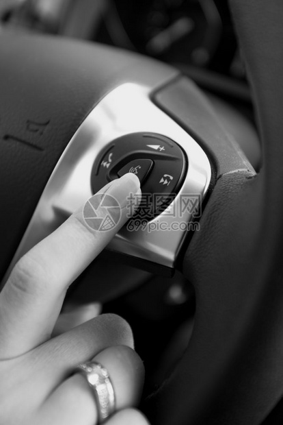 女驾驶员按方向盘按钮的黑白照片图片