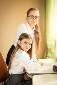 两个穿着校服的快乐女孩写作业图片