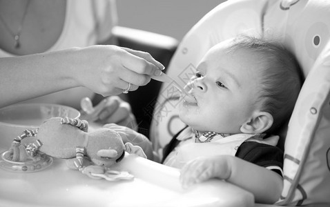 年轻笑的母亲喂养婴儿黑白画像图片