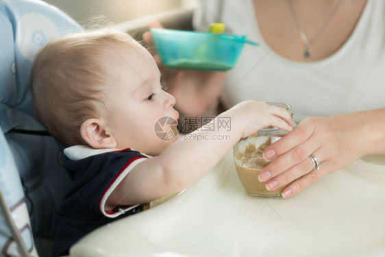 女人用苹果酱汤匙喂孩子图片