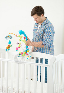 年轻男人在婴儿和小弟中附着玩具旋转木马图片